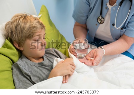 Elderly female pediatrician giving the medicine to her little patient