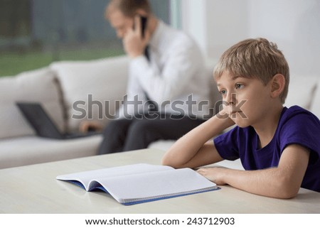 Dad working at home and bored son doing homework