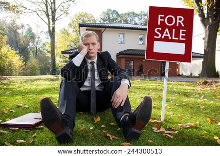Worried real estate agent and house for sale
