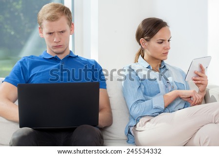 A man and a woman sitting together but alone online