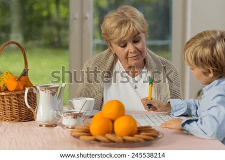 Cute little boy doing his homework with his lovely granny