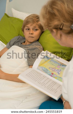Elderly nice granny reading the book to her little grandson