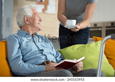Elderly happy man reading the book and his tea time