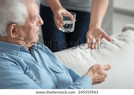 Female caregiver giving the medicine to her older male patient