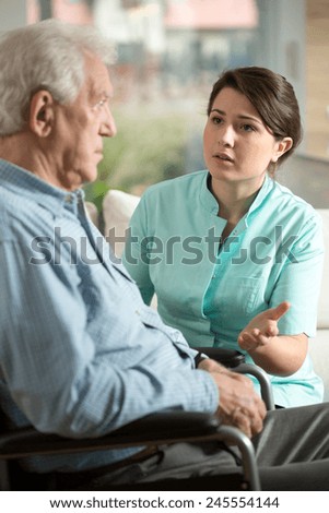 Young worried nurse talking with with older man