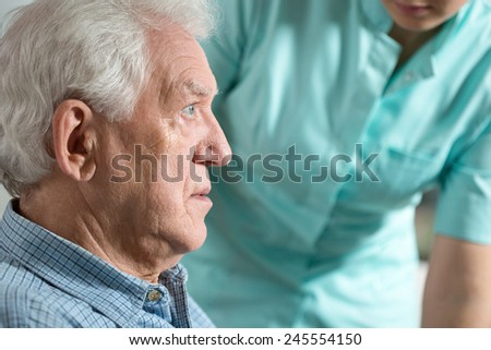 Close-up of elderly worried sick man sitting with nurse