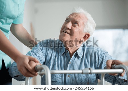 Close-up of aged man trying to stand up with walker
