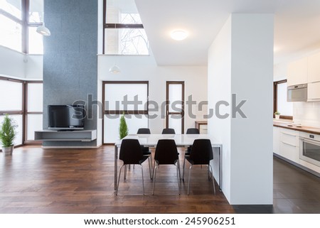 Big white table in spacious lounge with wooden floor