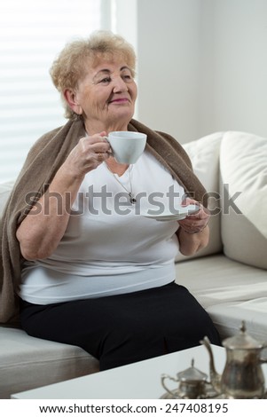 Senior woman sitting on the couch and drinking coffee