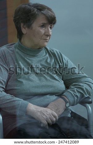 Vertical view of older melancholic woman sitting alone