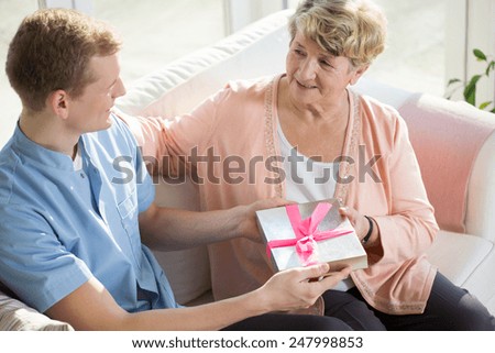 Young male nurse giving a present to older lady