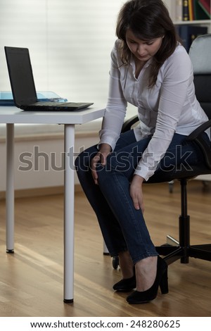 Young pretty secretary with high heels having pain in legs
