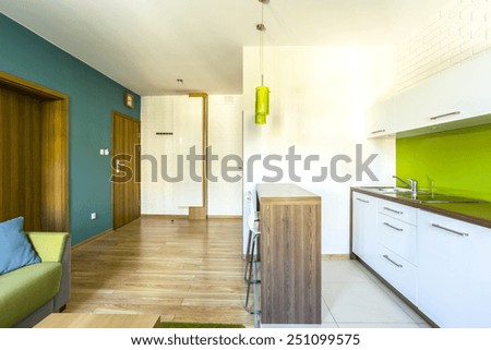 Spacious, green hotel room with modern kitchenette