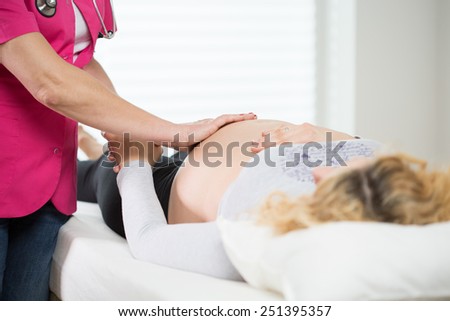 Experienced obstetrician examining pregnant woman\'s stomach