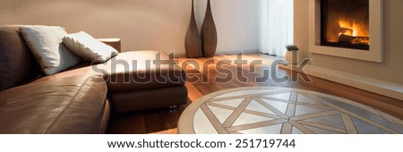 Leather sofa inside homely interior with fireplace