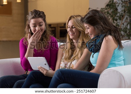 Three young pretty friends watching photos on tablet
