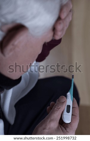 Close-up of ill elder man taking temperature