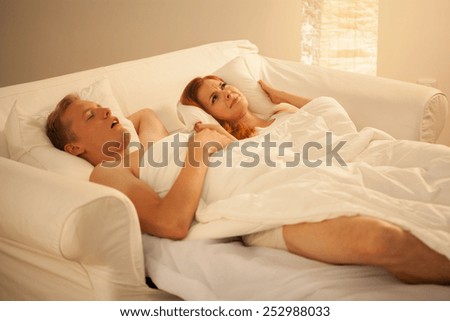 Snoring mans sleeping in bed with his irate wife