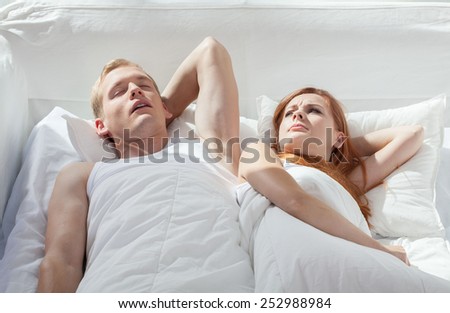 Dissatisfied woman looking at her boyfriend in bed