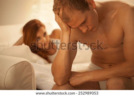 Young troubled man and his pleasant girlfriend in bed
