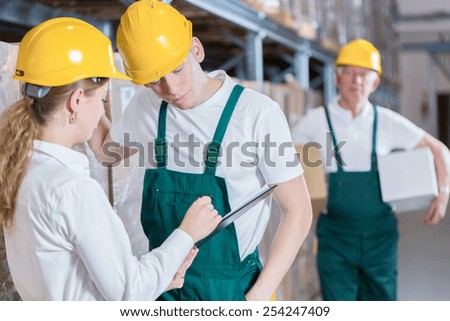 Young warehouseman having conversation with young female boss