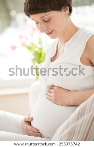 Young happy pregnant woman holding her belly
