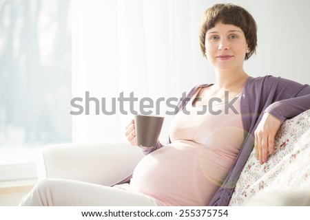 Young happy future mother resting on a couch