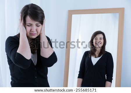 Young crying woman and her happy reflection