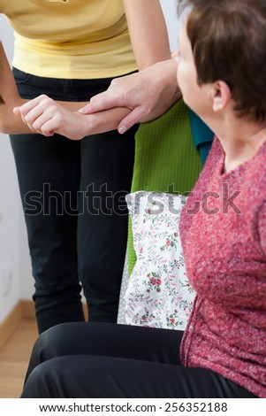 Sick woman supporting to young nurse's arm