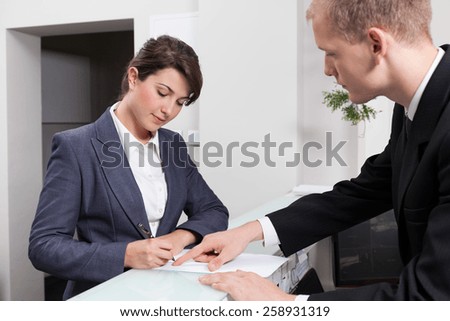 Horizontal view of attractive businesswoman signing document