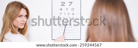 Ophthalmologist using Snellen chart to examine patient\'s vision