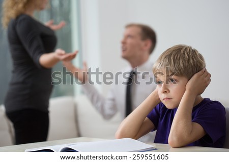 Sad little boy and family fight in living room