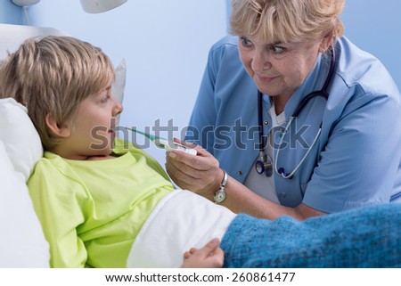 Senior pediatrician taking temperature of ill schoolchild