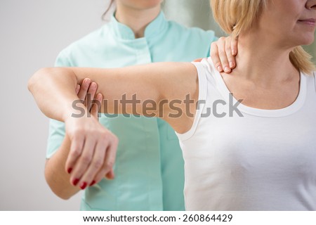 Physical therapist diagnosing patient with painful arm