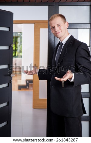 Estate agent stands at the entrance to the apartment and invites customers