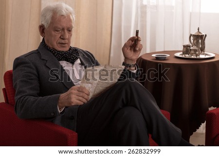 Elder man reading old letter and smoking cigar