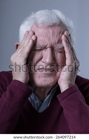 Aged sad man with acute pain in his head
