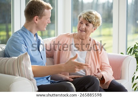 Male nurse and senior woman sitting on the couch