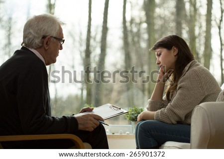 Young attractive sad woman sitting at psychologist\'s office