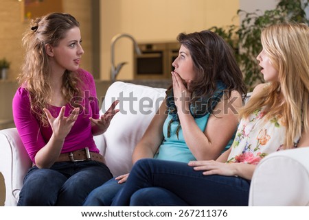 Young pretty woman telling the fascinating story to her girlfriends
