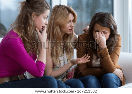 Two young worried girls supporting crying friend