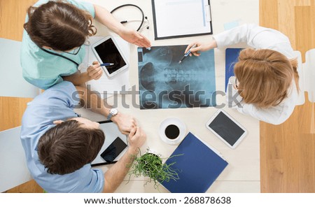 Three young physicians looking at xray of spinal column