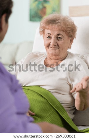 An old sick woman talking to her friend from bed