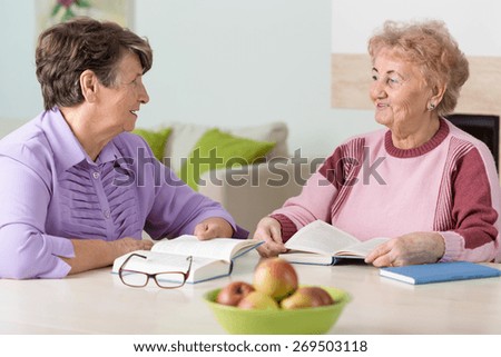 Two old women chatting over books and snacks