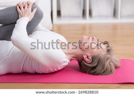 Mature woman training on the exercise floor mat