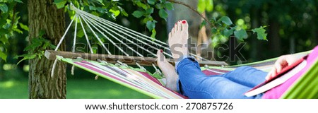 Young girl resting on hammock with book summer