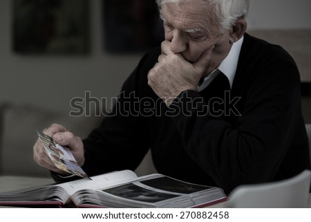 Senior sad man with photo missing his wife