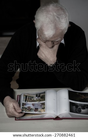 Older man with photo album recollecting old times
