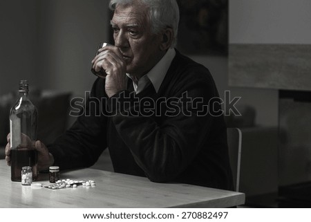 Photo of older sad man drinking alcohol alone