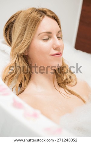 Blonde woman relaxing during bath with foam